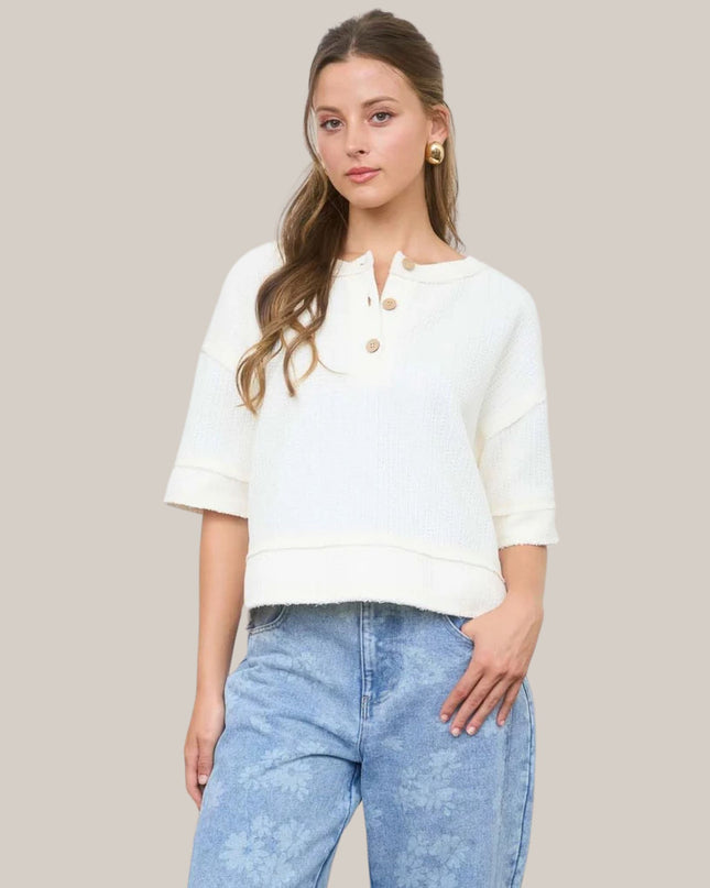 Woman wearing a white blouse with rolled-up sleeves and light blue jeans on a plain background