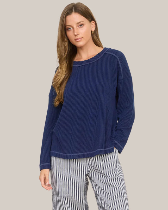 Woman wearing a blue sweater and striped pants on a plain background