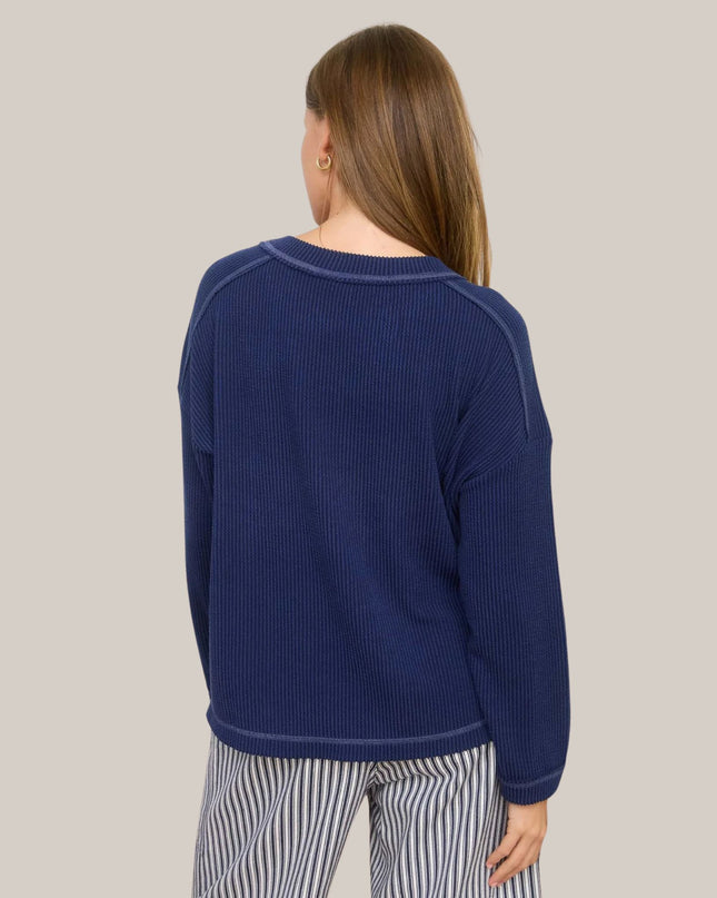 Person wearing a blue ribbed sweater on a plain background