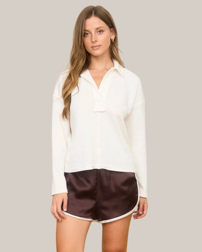 Woman wearing a white shirt and brown shorts on a plain background