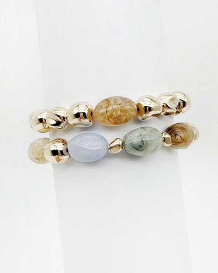 Two beaded stretch bracelets displayed on a white background. One bracelet features metallic gold beads and a central marbled brown bead.