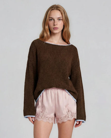A woman modeling a brown fuzzy knit long-sleeve top with light blue trim, paired with light pink lace-trimmed shorts, against a plain light gray studio background.