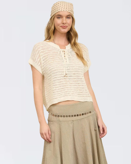 Woman wearing a beige crochet top and skirt with a headband on a light gray background