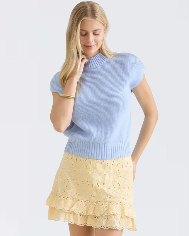 Woman wearing a light blue sweater and yellow skirt on a white background