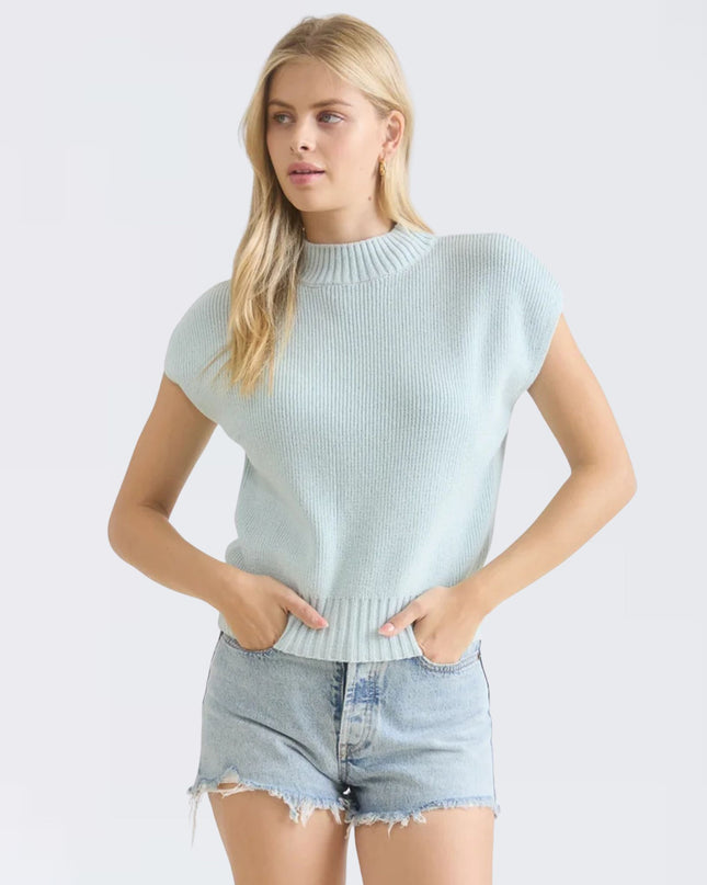 Woman wearing a light blue sweater and denim shorts on a white background