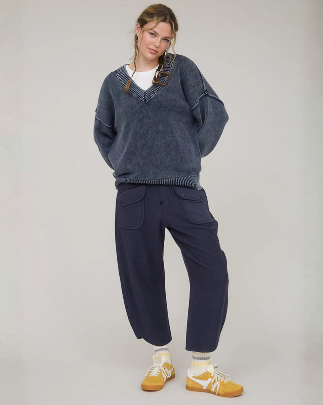 Person wearing a blue sweater and navy pants with yellow shoes on a plain background
