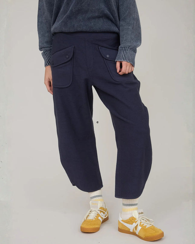 Person wearing navy pants, gray sweater, yellow shoes, and striped socks on a plain background