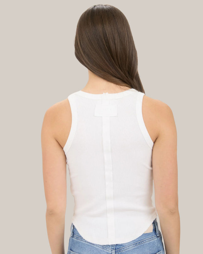 Person wearing a white sleeveless top and blue jeans on a plain background