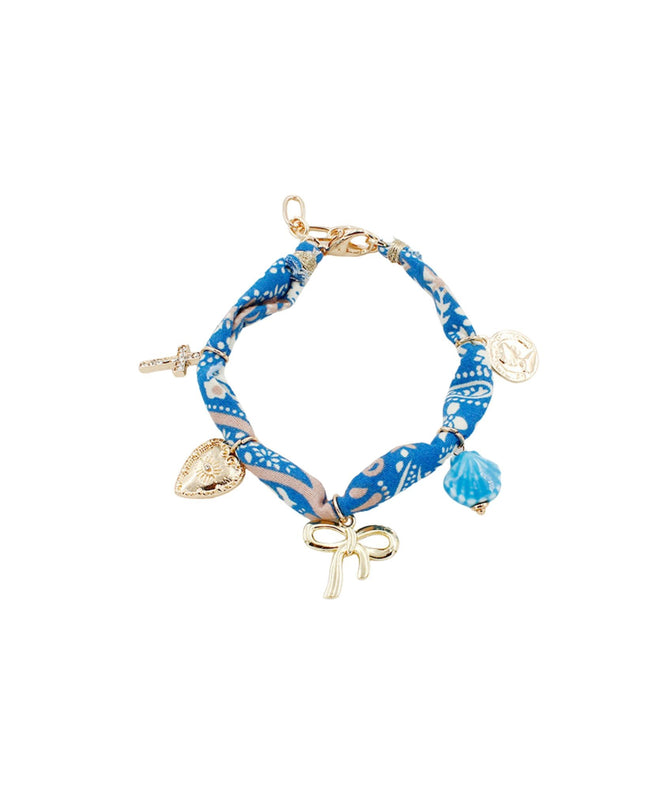 A charm bracelet featuring a blue and white patterned fabric wrap, gold-plated metal clasp and charms, and a small blue bead, shown on a plain white background.