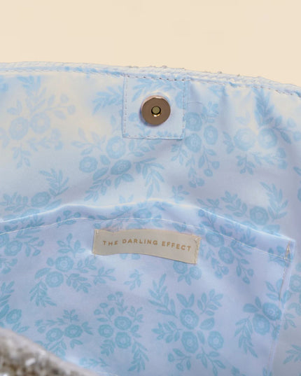 Floral-patterned fabric with a button and 'The Darling Effect' label on a beige background