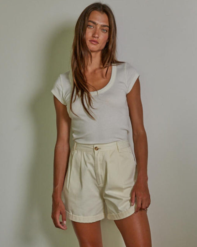 Woman wearing a white t-shirt and beige shorts against a plain background