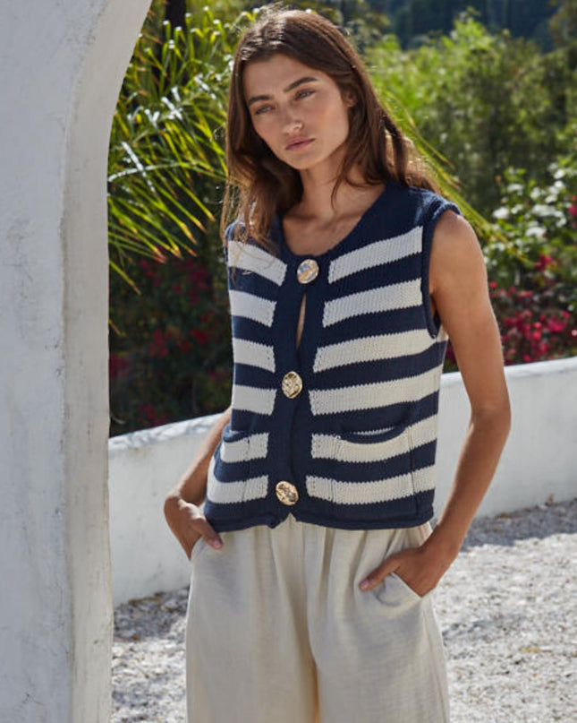 Woman wearing a navy and white striped sleeveless cardigan in an outdoor setting.