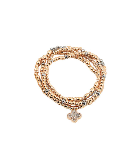 A multi-strand beaded stretch bracelet in rose gold and silver, featuring a small pavé four-leaf clover charm at the center, shown on a plain white background.