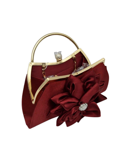 A burgundy satin evening handbag with a gold-tone metal frame, a top handle, and a large decorative satin flower embellishment on the front, accented with a rhinestone-like center.