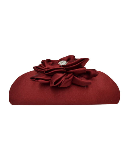 A burgundy satin clutch purse featuring a large fabric flower embellishment on top with a small silver rhinestone center, shown against a plain white background.