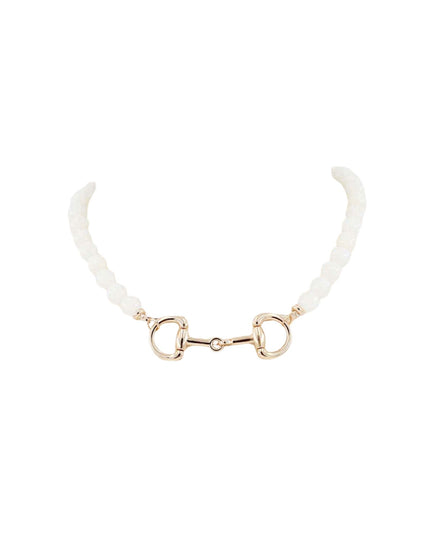 A delicate horsebit necklace featuring a gold-tone metal bit centerpiece and cream-colored textured beads on either side, set against a solid white background.
