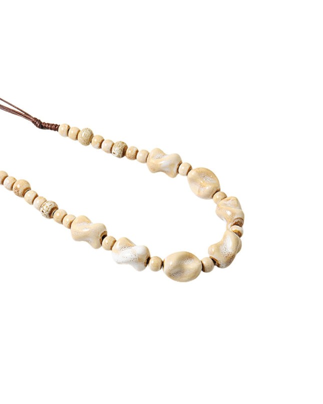 A beaded necklace featuring natural cowrie shells and small wooden beads on a brown cord, shown against a plain white background.