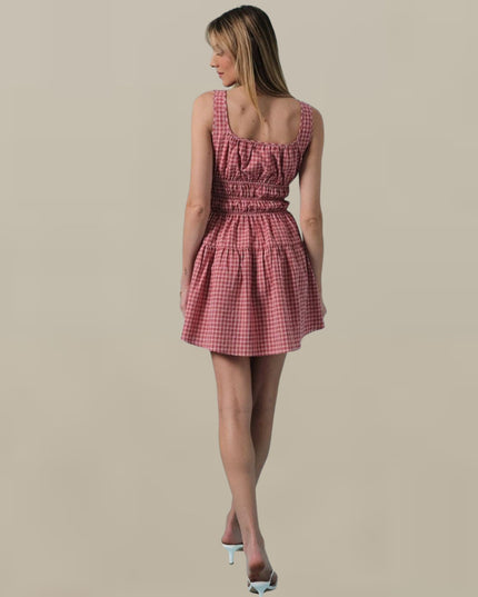 Woman wearing a pink checkered dress on a beige background