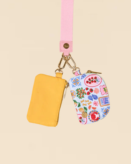 Yellow pouch with floral design on a pink strap against a beige background
