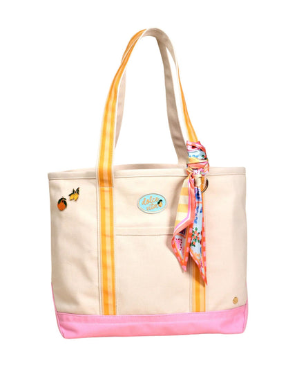 Beige tote bag with yellow handle and pink base, featuring a colorful scarf and decorative elements on a white background.