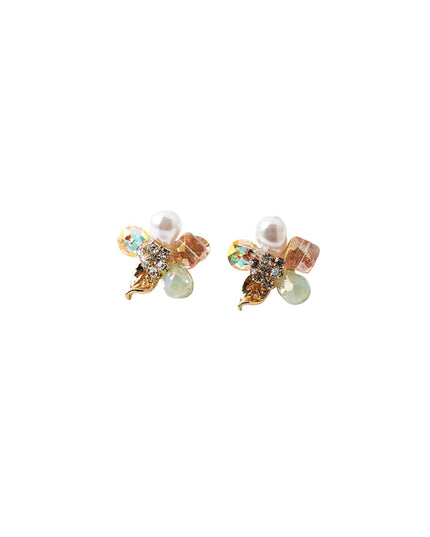 A pair of gold-toned flower stud earrings featuring white faux pearls, iridescent rhinestone wings, and light green faceted beads, set against a plain white background.