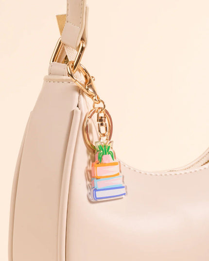 Beige handbag with a colorful keychain attached on a beige background