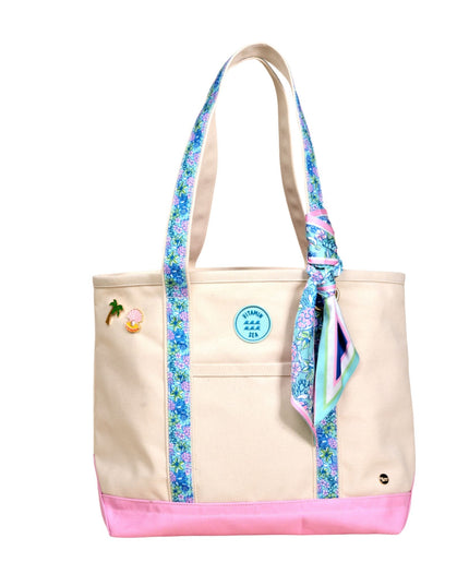 Beige tote bag with floral straps and pink bottom section on a white background
