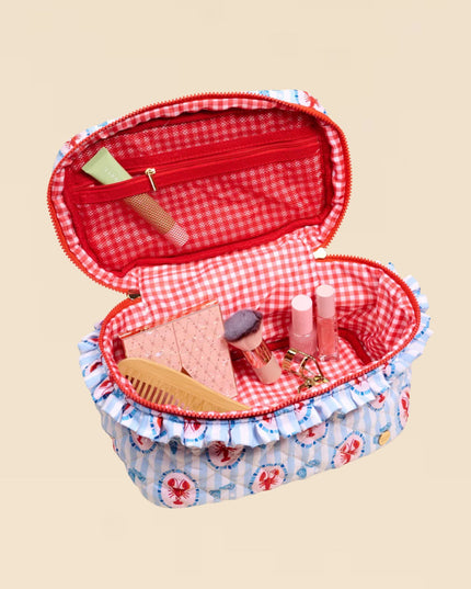 Open red and blue checkered makeup case with cosmetic items on a beige background