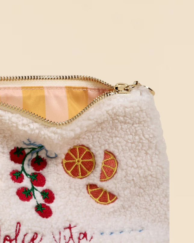 White pouch with embroidered fruit designs and 'dolce vita' text on a beige background