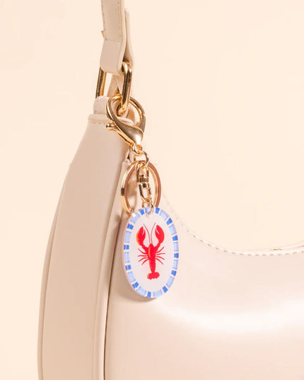 Beige handbag with a lobster charm on a beige background