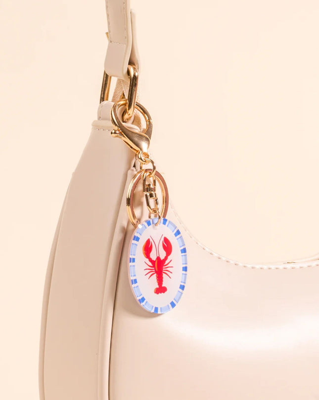 Beige handbag with a lobster charm on a beige background