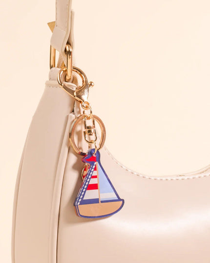 Sailboat keychain attached to a beige handbag