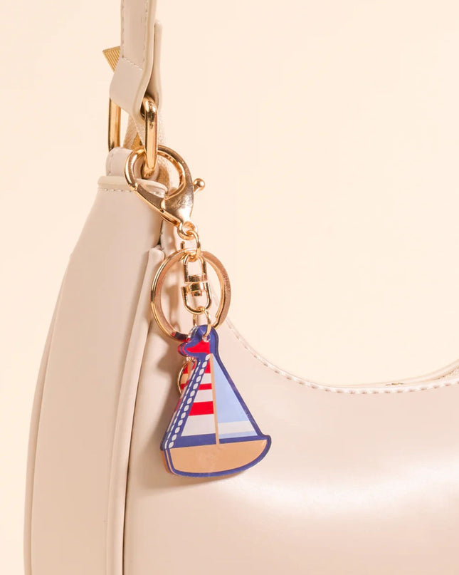 Sailboat keychain attached to a beige handbag
