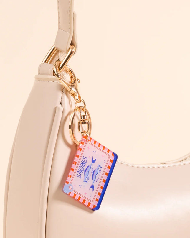 Beige handbag with a decorative keychain on a beige background