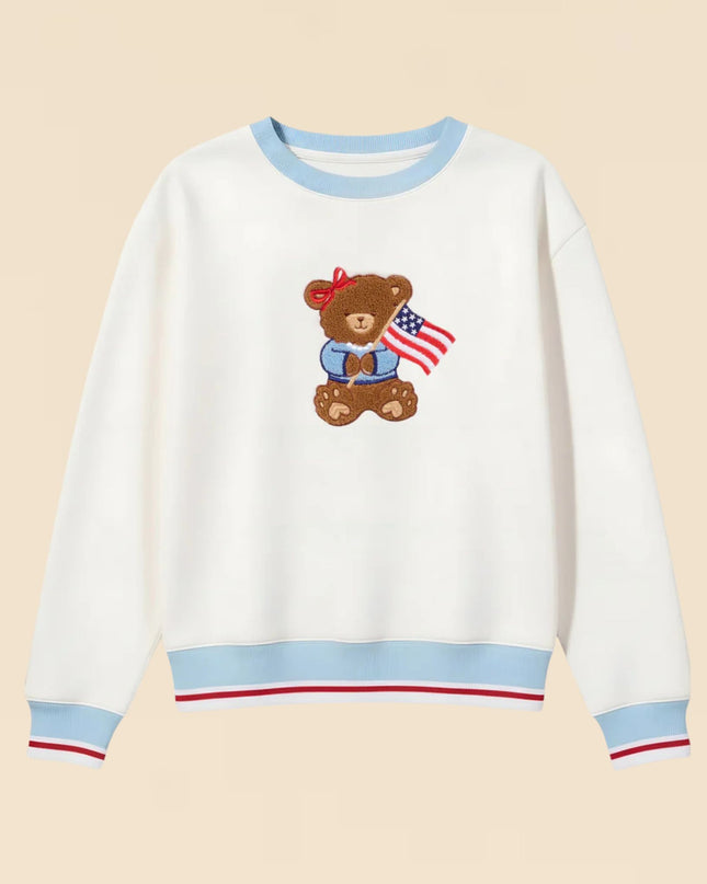 White sweatshirt with a teddy bear and American flag design on a beige background