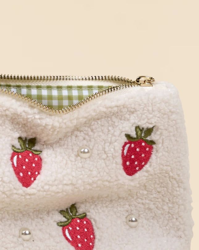 White pouch with strawberry patterns and pearl embellishments on a beige background