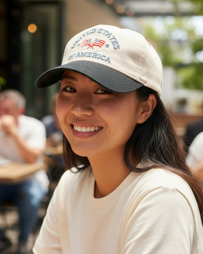 Woman wearing a cap with 'United States of America' text, smiling outdoors.