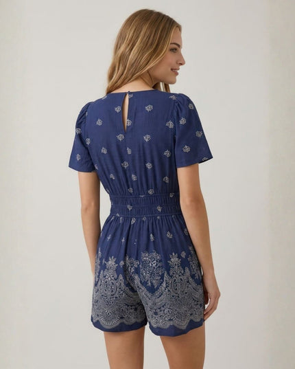 Woman wearing a blue patterned romper against a plain background
