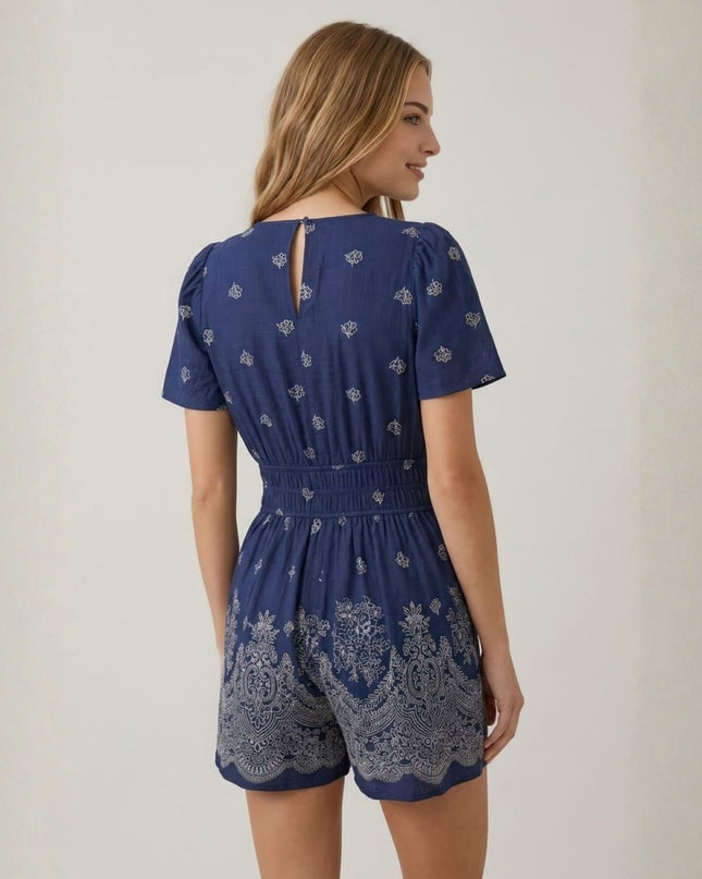 Woman wearing a blue patterned romper against a plain background
