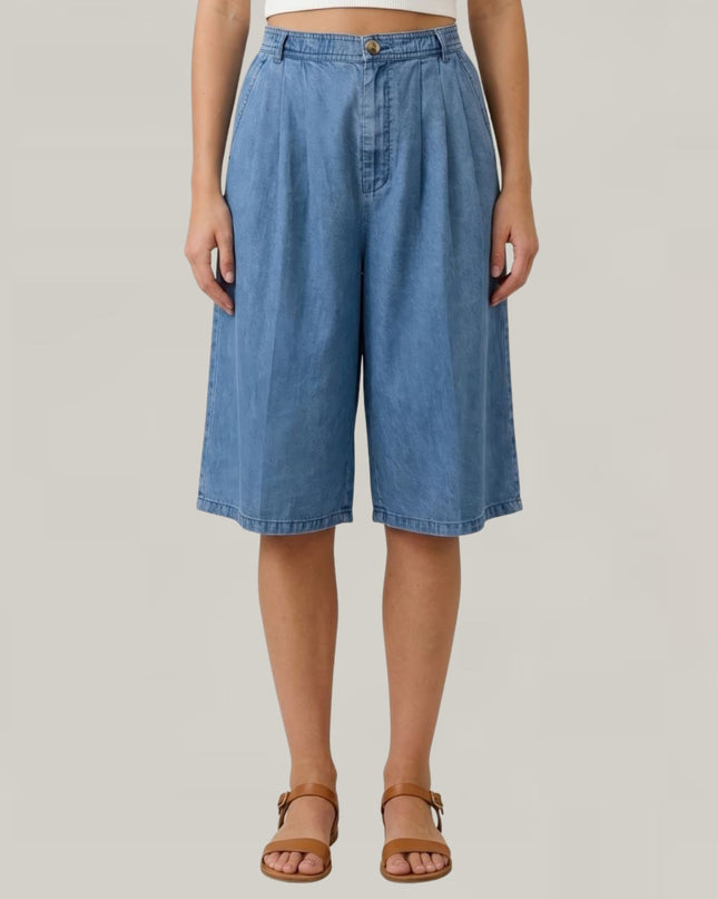 Person wearing blue denim shorts on a plain background