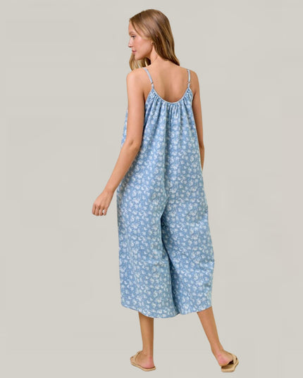 Woman wearing a blue floral jumpsuit on a gray background