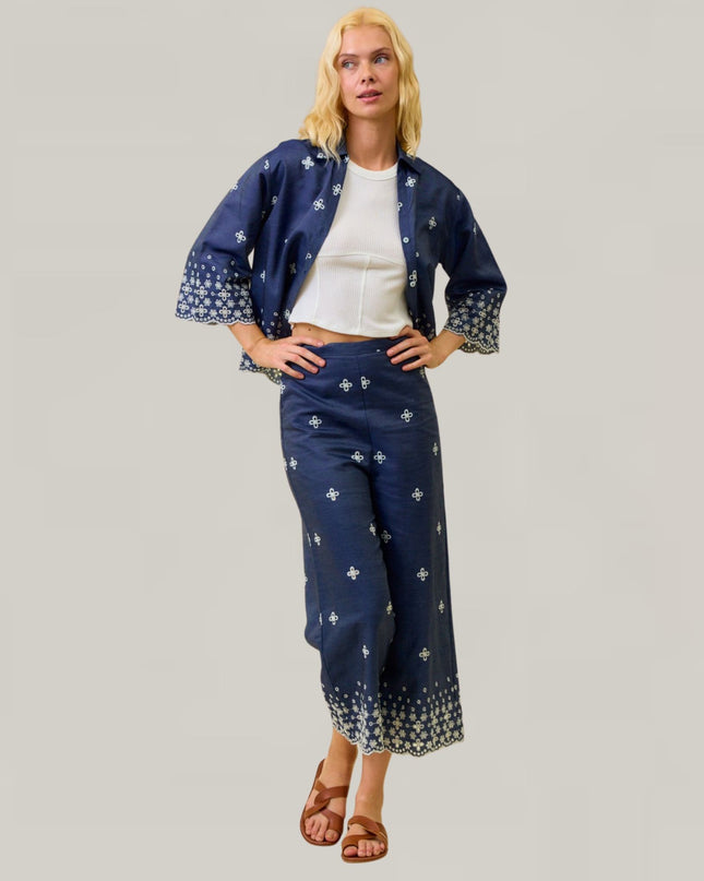 Woman wearing a navy blue outfit with white patterns on a gray background