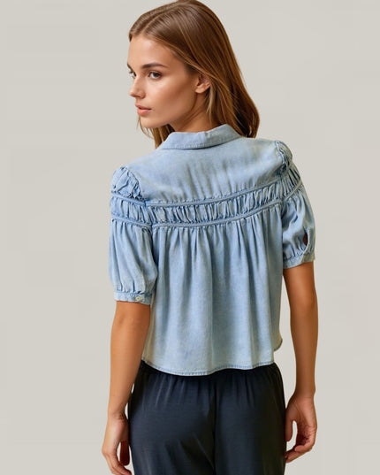 Woman wearing a light blue denim blouse against a plain background