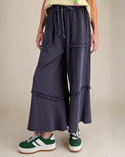 Person wearing navy blue layered pants with a plain background