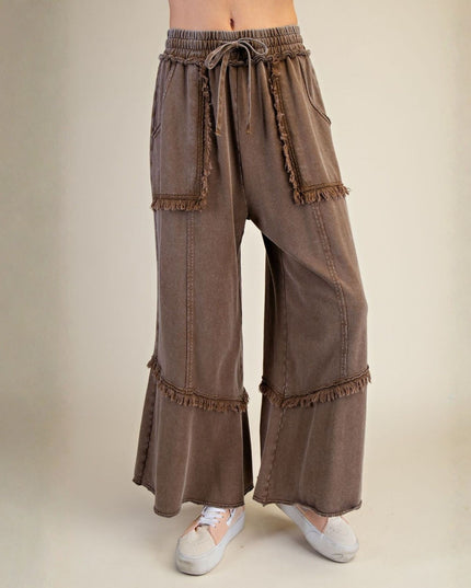 Brown wide-leg pants with ruffled details on a beige background