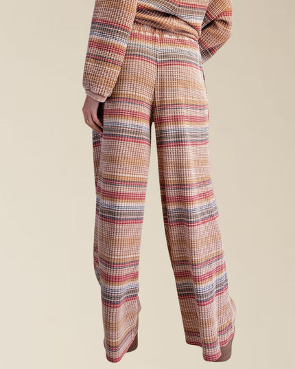 A person wearing wide-leg plaid trousers with a matching top, shown from the waist down against a plain beige studio background.