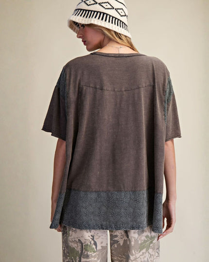 Person wearing a brown and gray layered top with a patterned hat on a beige background