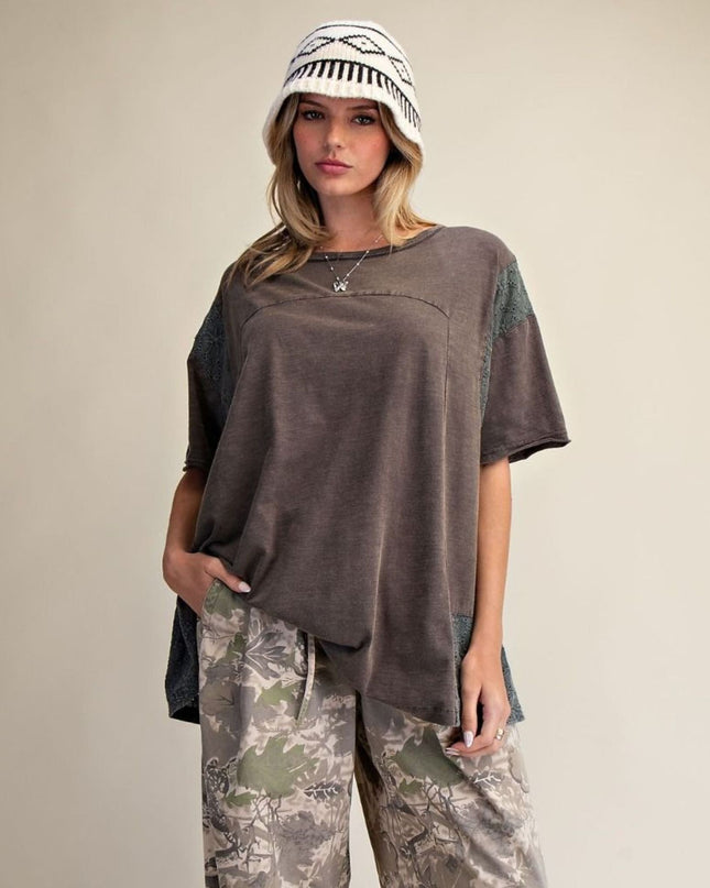 Woman wearing a brown oversized shirt and camouflage pants with a beige background