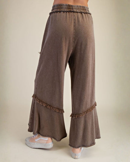Brown wide-leg pants with frayed hems on a beige background