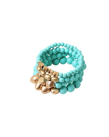 A stack of three beaded stretch bracelets in a vibrant turquoise color, featuring a central cluster of textured metallic gold flower-shaped beads, shown on a plain white background.
